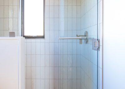 Shower with glass surround and white subway tile in a vertical pattern.